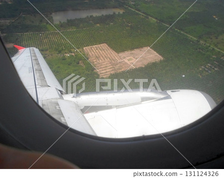 An Aerial View of Lush Greenery and Fields Through an Airplane Window During Flight 131124326