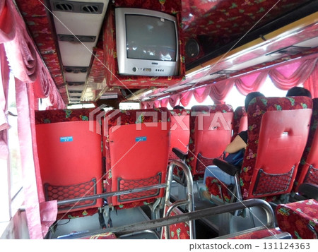 Interior of a Bus with Red Seats and Floral Curtains Featuring a Ceiling TV Interior of a Bus with Red Seats and Floral Curtains Featuring a Ceiling TV 131124363