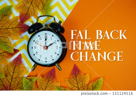 Fall Back Time Change with alarm clock and maple leaf decorated on orange background 131124518