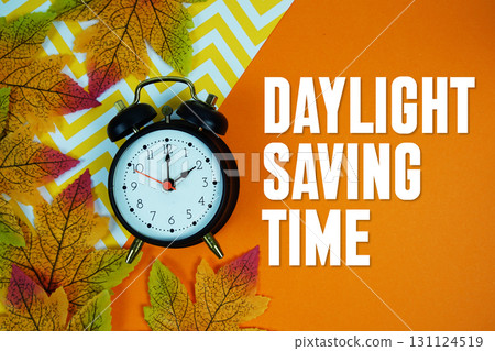 Daylight Saving Time with alarm clock and maple leaf decorated on orange background 131124519