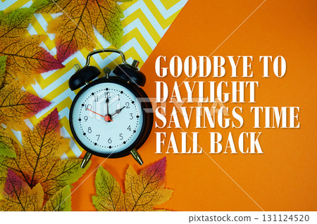Goodbye To Daylight Savings Time Fall Back with alarm clock and maple leaf decorations on orange background 131124520