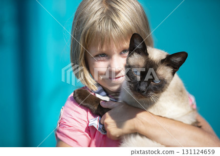 A little girl holds a kitten in her arms and looks at the camera. A little girl holds a kitten in her arms and looks at the camera. 131124659