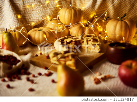 Cozy Autumn Thanksgiving Scene With Pumpkins, Pies, Apples, And Warm Fairy Lights Cozy Autumn Thanksgiving Scene With Pumpkins, Pies, Apples, And Warm Fairy Lights 131124817