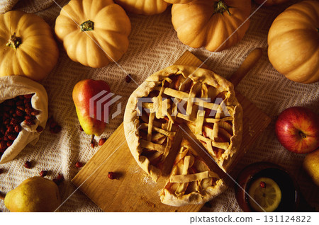 Autumn Thanksgiving Table Scene With Pumpkin Pie, Small Pumpkins, Apples, and Harvest Fruits 131124822