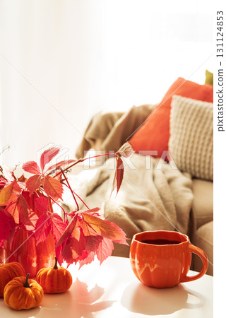 Cozy Autumn Living Room Scene with Mug, Notebook and Seasonal Decor under Sun Light 131124853