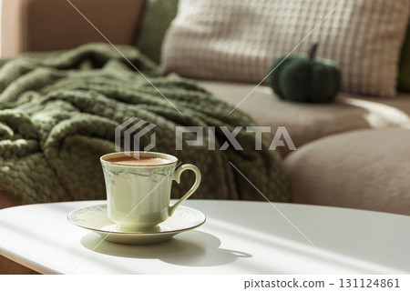 Cozy Autumn Scene with Green Cup of Coffee and Sofa Decor 131124861