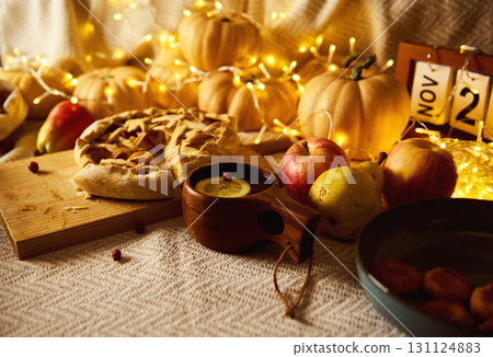Cozy Autumn Thanksgiving Table Scene With Pies, Fruit, Pumpkins, Fairy Lights and Warm Glow 131124883