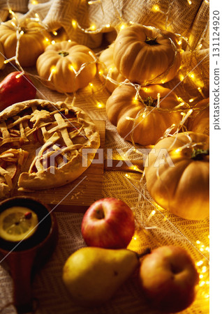 Autumn Harvest Table With Pumpkin Pie, Apples, Pears, And Cozy Fairy Lights Autumn Harvest Table With Pumpkin Pie, Apples, Pears, And Cozy Fairy Lights 131124920