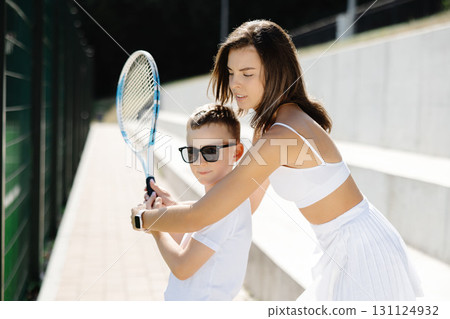 Female tennis coach teaching young boy how to hold racket properly 131124932