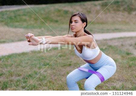 Young woman exercising with dumbbells in a park, promoting healthy lifestyle and fitness 131124946