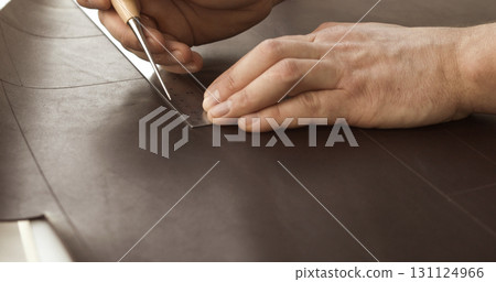 Craftsman measuring and marking brown leather material with ruler and tool Craftsman measuring and marking brown leather material with ruler and tool 131124966