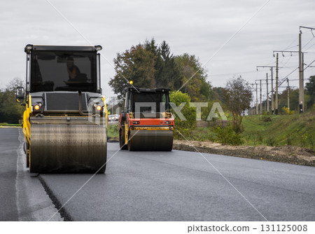Two heavy road rollers compacting asphalt surface during construction work 131125008