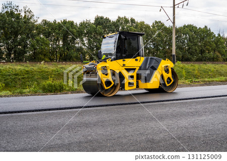 Yellow road roller compacting asphalt during construction and roadwork 131125009