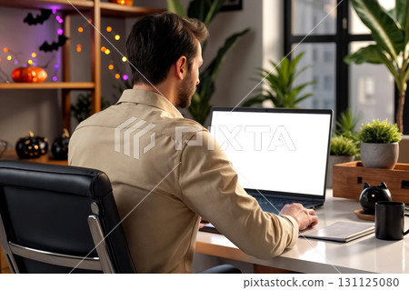 young man working on laptop in home office decorated for halloween, mockup of workspace 131125080