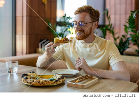Man with ginger hair and braces eating pizza in restaurant Man with ginger hair and braces eating pizza in restaurant 131125131