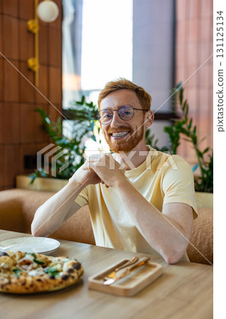 Redhead man enjoying lunch indoors with pizza on plate 131125134