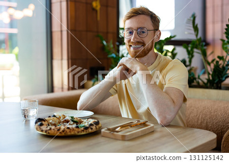 Bearded redhead man wearing glasses happily eating pizza 131125142