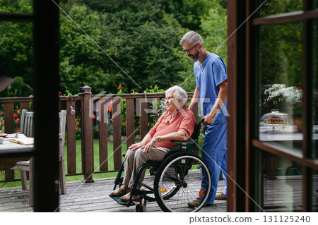 Male home nurse taking care of elderly woman in wheelchair. Male home nurse taking care of elderly woman in wheelchair. 131125240