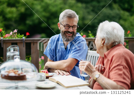 Caregiver spending time with elderly woman, drinking coffee and talking. Caregiver spending time with elderly woman, drinking coffee and talking. 131125241