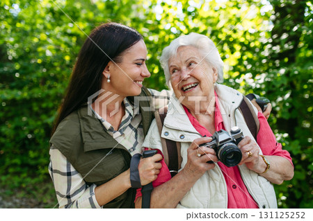 Senior woman and daughter enjoying hike with trekking poles. Senior woman and daughter enjoying hike with trekking poles. 131125252