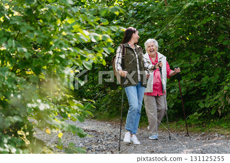 Senior woman and daughter enjoying hike with trekking poles. 131125255