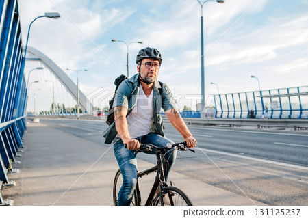 City commuter riding bike to work, wearing backpack and helmet. 131125257