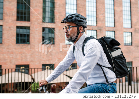 City commuter riding bike to office, wearing backpack and helmet. City commuter riding bike to office, wearing backpack and helmet. 131125279