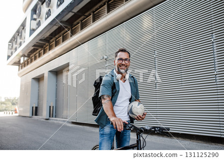 City commuter riding bike on street, wearing backpack. 131125290