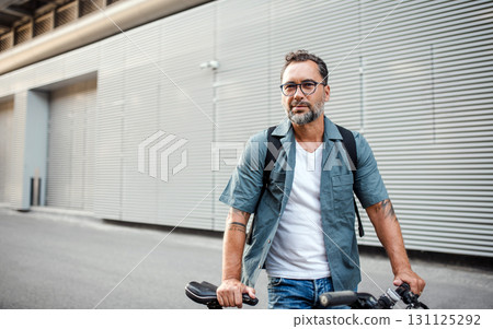 City commuter riding bike on street, wearing backpack. 131125292