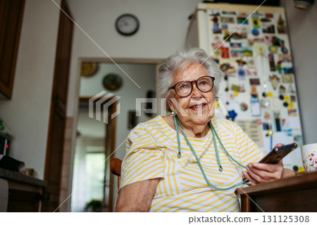 Portrait of senior woman holding smartphone at home. 131125308
