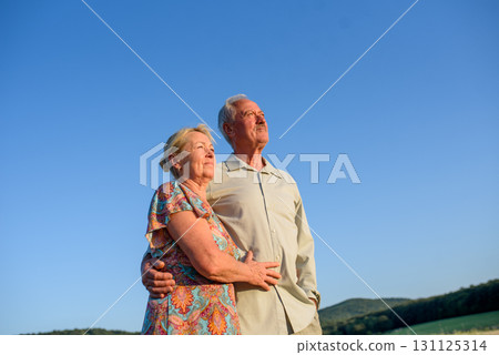 Happy senior couple embracing in meadow at sunset. 131125314