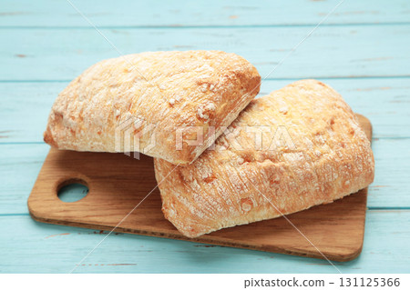 Ciabatta rustic bread on cutting board on blue background. 131125366