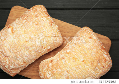 Ciabatta rustic bread on cutting board on black background. Ciabatta rustic bread on cutting board on black background. 131125368