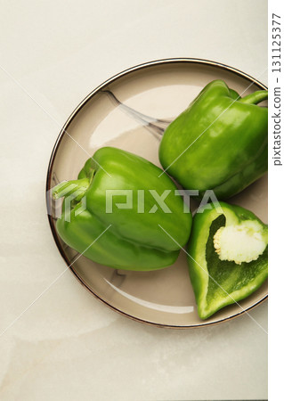 Green sweet pepper bell on plate on light background. Vertical photo 131125377
