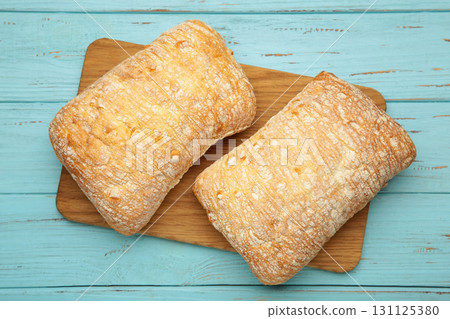 Ciabatta rustic bread on cutting board on blue background. Ciabatta rustic bread on cutting board on blue background. 131125380