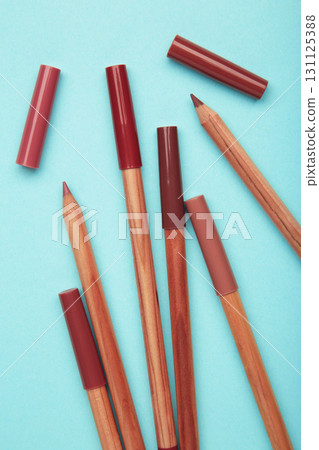 Different lip pencils on blue background. Cosmetic product. Vertical photo 131125388