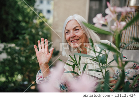 Beautiful senior neighbor waving at someone on street. Beautiful senior neighbor waving at someone on street. 131125424