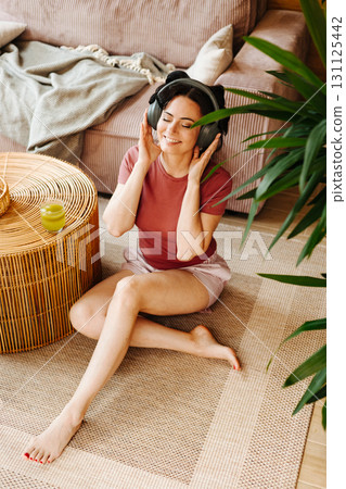 Woman relaxing at home with hair rollers and headphones 131125442