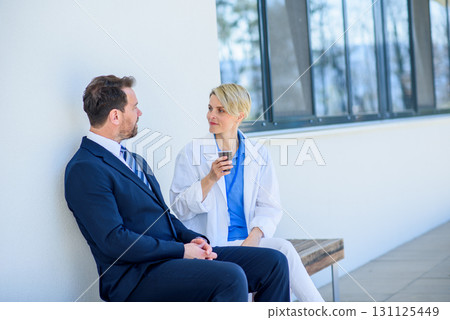 Doctor and pharmaceutical representative talking about new drug, in front of hospital. Doctor and pharmaceutical representative talking about new drug, in front of hospital. 131125449