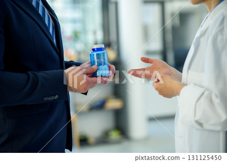 Doctor and pharmaceutical representative talking about new drug, clinical setting. Doctor and pharmaceutical representative talking about new drug, clinical setting. 131125450
