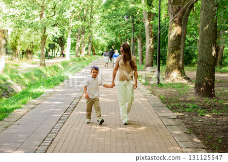 Mother and son walking holding hands during sunny summer day. Family bonding concept. 131125547