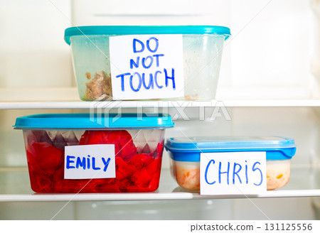 Do Not Touch sticker on lunch boxes in office refrigerator. Angry and hungry workers concept. 131125556