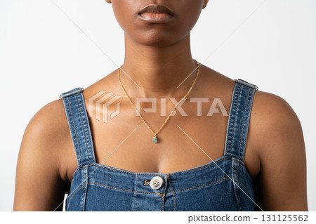 Close-up of woman wearing gold necklace with green gemstone pendant 131125562