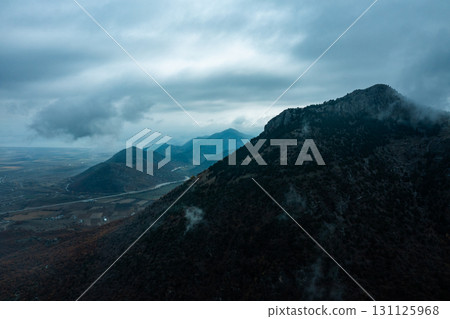 Moody mountain landscape with dramatic clouds and misty atmosphere 131125968