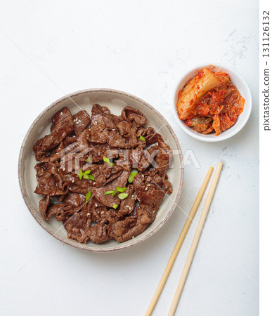 Bulgogi, grilled marinated beef Korean dish with kimchi and sesame seeds top view on white background Bulgogi, grilled marinated beef Korean dish with kimchi and sesame seeds top view on white background 131126132