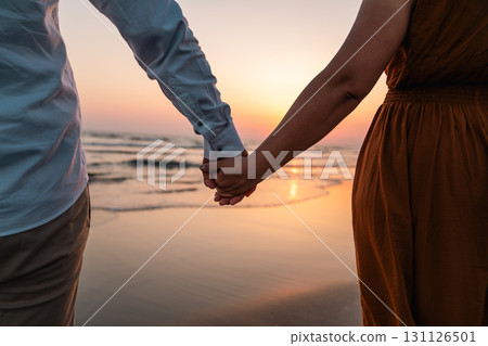 Couple holding hands at beach during sunset Couple holding hands at beach during sunset 131126501