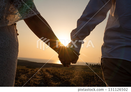 Couple holding hands at sunset with romantic view 131126502