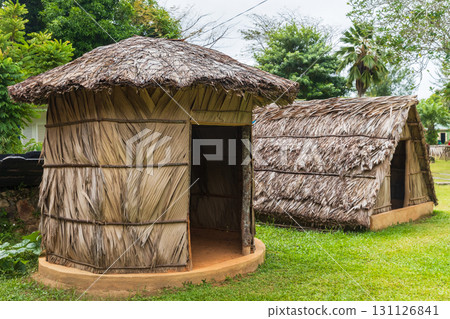 A pair of traditional thatched huts stand on grassy ground in a lush. Mahe, Seychelles A pair of traditional thatched huts stand on grassy ground in a lush. Mahe, Seychelles 131126841