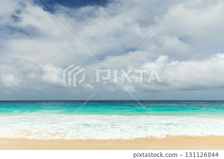 A tranquil beach scene with turquoise water, white sand, and gentle waves 131126844