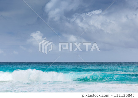 Vibrant seascape featuring turquoise waves rolling onto a white-sand shore 131126845
